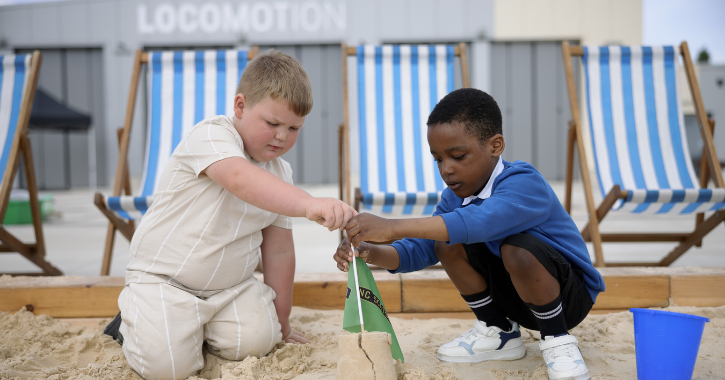 Two young boys playing in the popup beach and building at sandcastle at Locomotion museum.